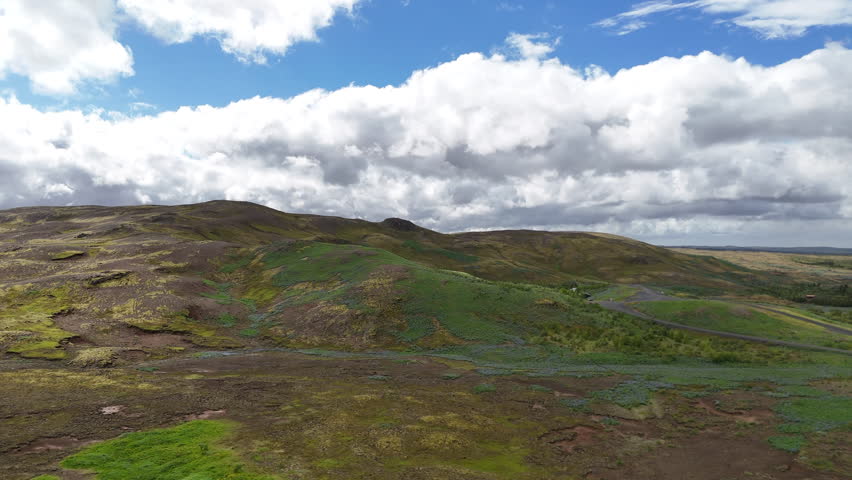 Aerial drone view of vast empty fields and rolling mountains near Reykjavik, Iceland, under dramatic clouds, showcasing untouched volcanic landscapes and remote Nordic wilderness.