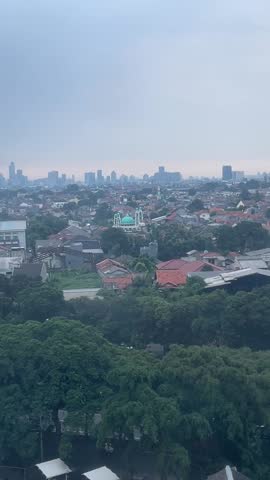 JAKARTA, INDONESIA - NOVEMBER 11, 2023: High angle aerial view from the 8th floor of a building overlooking a dense urban cityscape during a bright golden sunset. Modern buildings and city skyline illuminated by warm afternoon sunlight.