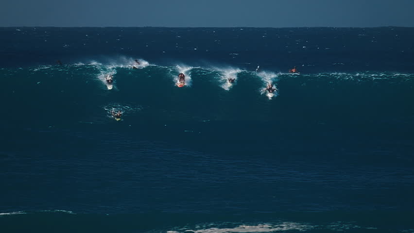 Big wave surfing in Hawaii on Waimea Bay. People surf the huge ocean wave breaking on the Hawaiian shore in Waimea Bay. Surfers share the wave in Hawaii. Oahu island