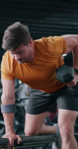 Dumbbell, weightlifting and man in gym for exercise, training and fitness for endurance goals. Bodybuilder, person or athlete with arm strength, power workout or health challenge in sports center