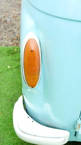 Close up of old blue van front detail on green grass with orange blinker light