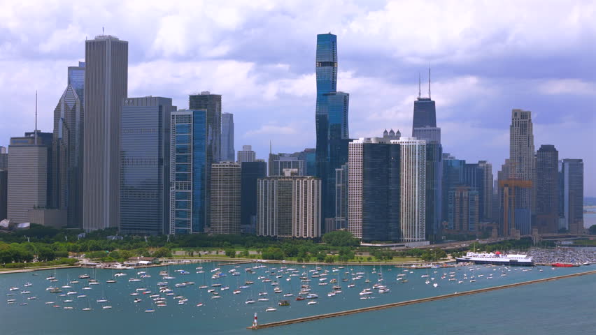 Aerial view of Chicago Illinois waterfront with marina filled with boats, Lake Michigan shoreline, green parks, urban coast, summer light, calm water, and city lifestyle