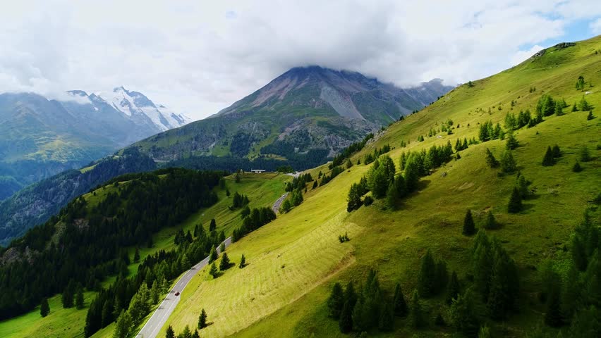 Slow drone flight along Grossglockner road with clouds hugging peaks high