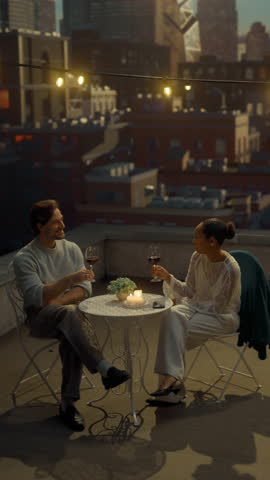 Vertical Screen: Romantic Couple Enjoys Intimate Rooftop Dinner Date at Sunset, Clinking Wine Glasses, Laughing and Talking Around a Candlelit Table, Loving Relationship, City Evening Lifestyle Vibes