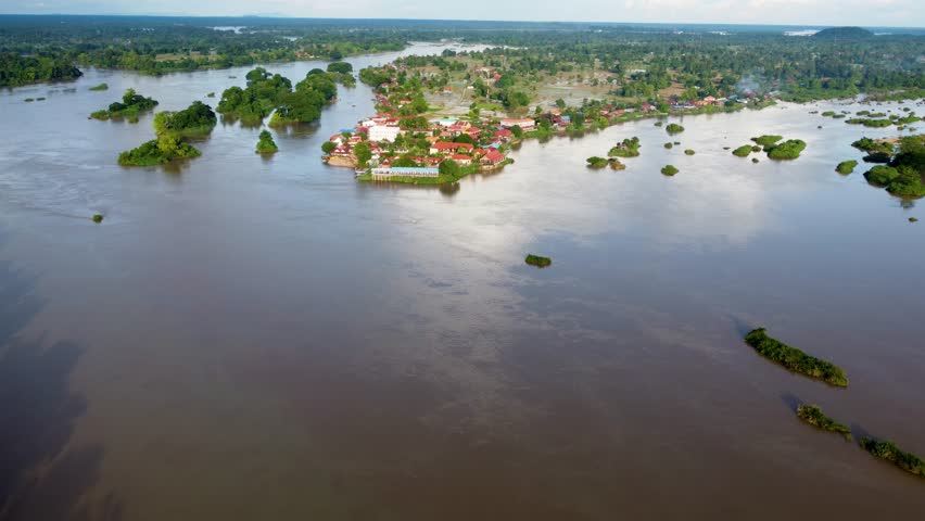 Aerial clip showing a riverside settlement and surrounding rice paddies on Don Det island along the Mekong River in Laos.