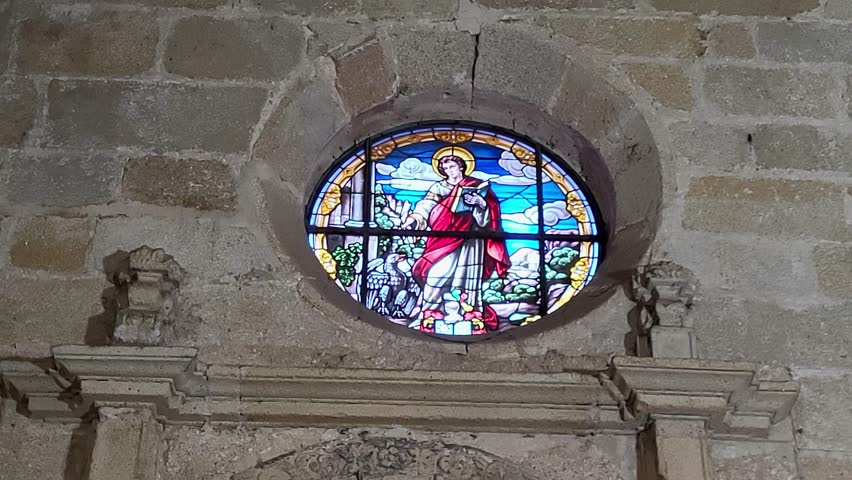 Stained glass windows and Gothic arches inside a medieval Spanish cathedral. Stained glass windows with vibrant colors set in granite stone arches. Religious architecture. Gothic art. Caceres. Spain.