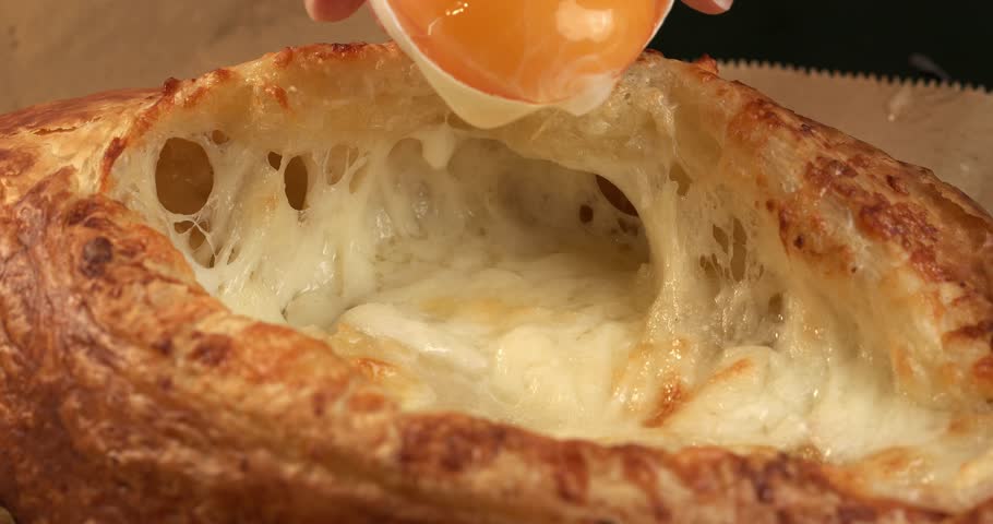 Egg yolk is added to Adjarian Khachapuri, close-up footage.