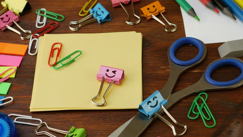 Stationery layout for student workspace. Binder clip, correction tape, ruler, paperclip, pencil, metal pen, eraser, scissors, paper sheet. Office and school supplies offer functionality and efficiency