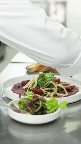 Chef, hands and plate in restaurant kitchen with food preparation, onion garnish and culinary skills. Person, cooking and healthy meal in diner with hospitality, catering and aesthetic presentation.