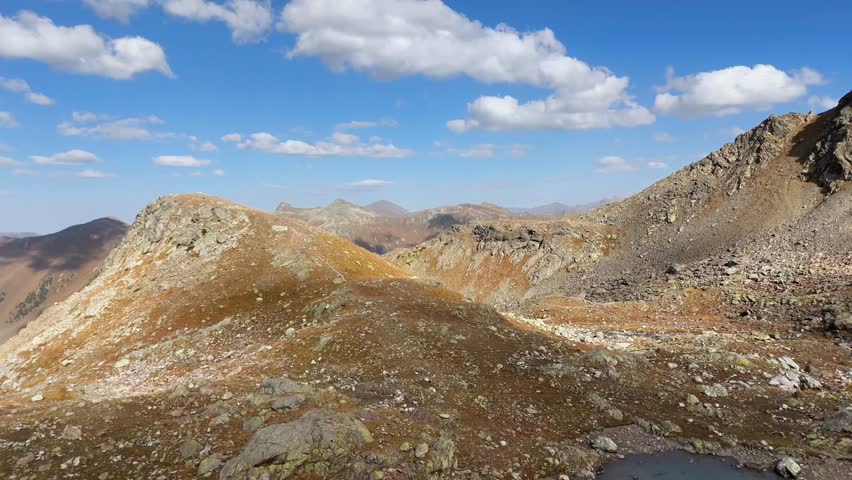 A large body of water sits in the middle of a rocky, barren landscape. The water is a deep blue color, and the sky above is clear and blue. The scene is peaceful and serene
