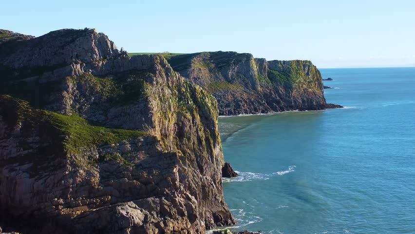 Descending Parallax Drone View of Dramatic Cliffs on Gower Coastline on Beautiful Day with Calm Seascape. Hiking Area Tourist Holiday Desintation.