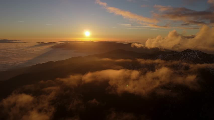 Sunset above a sea of fog and low clouds with mountain ridge aerial view of foggy mountains