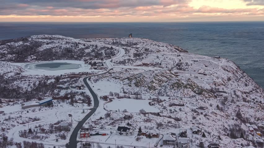 An expansive view from Signal Hill overlooking snow covered hills and the Atlantic Ocean under a pastel sky.