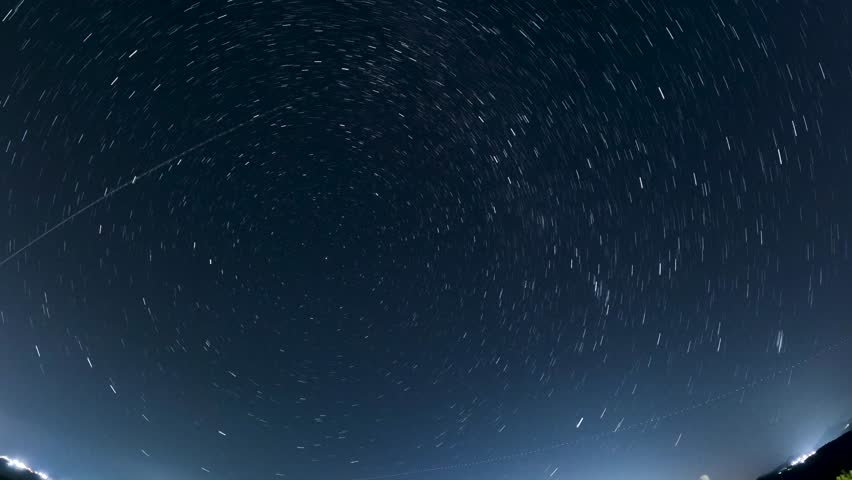 Mesmerizing circular star trails time lapse rotating around the North Star Polaris in a clear night sky, creating a vortex effect over a dark landscape in Corfu Greece.