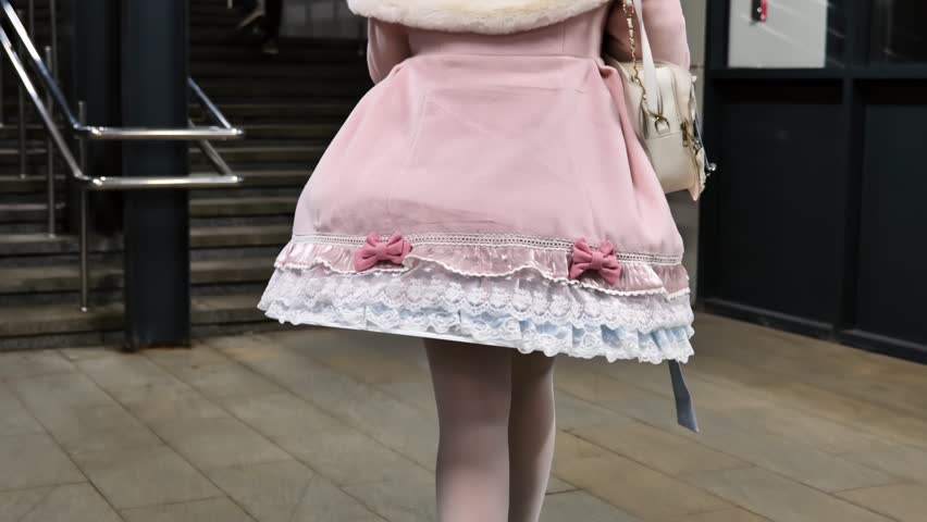 Young woman wearing pink lolita fashion dress with lace trim and bows