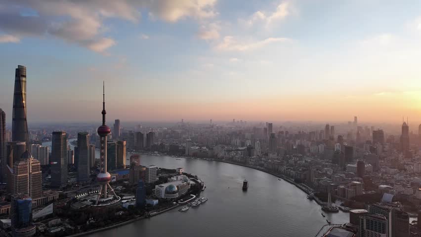 Shanghai, China: Cinematic aerial panoramic footage of a the sunset over Shanghai cityscape and skyline with the Hangpu river, the Bund riverside and the Pudong financial district in China. 