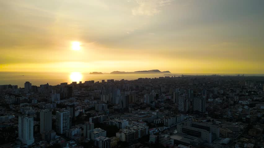 Aerial drone footage of golden sunset over Lima, Peru with Pacific Ocean horizon.