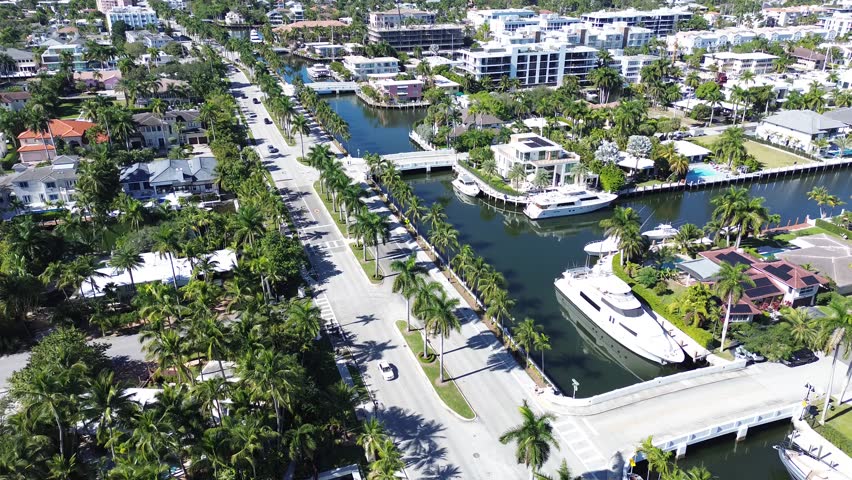 Aerial drone footage flying through Fort Lauderdale showing residential neighborhoods, waterfront homes, and the famous canal system creating a luxury coastal city atmosphere in South Florida. Ideal for travel, tourism, real estate, and lifestyle concepts.