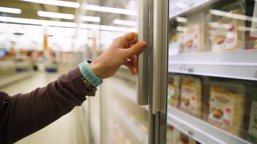 Girl Opens The Freezer And Takes Ravioli While Shopping In The Supermarket