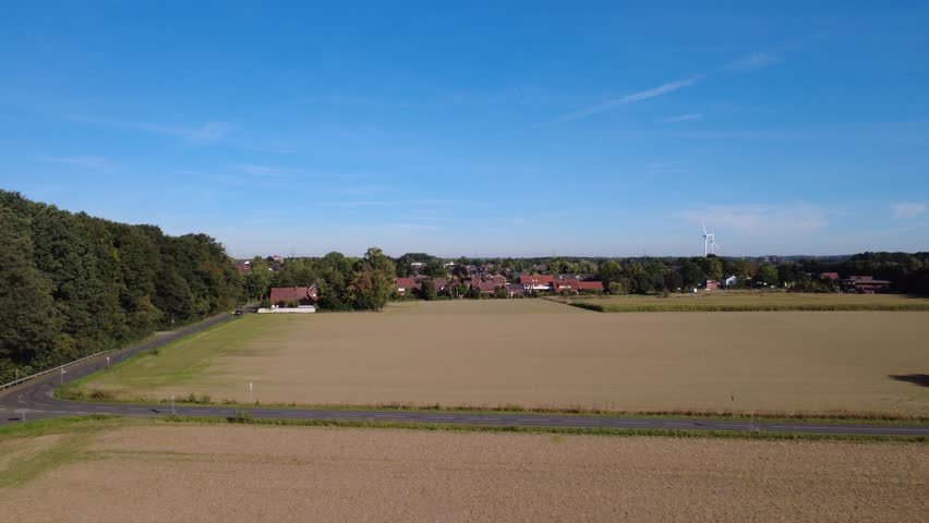 Aerial view of rural landscape with fields and forest under blue sky