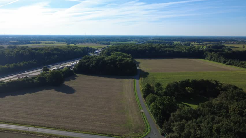 Aerial view of rural landscape with fields and forest under blue sky