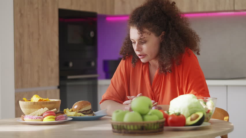 Motivated woman eating grape instead of junk food, healthy weight loss diet