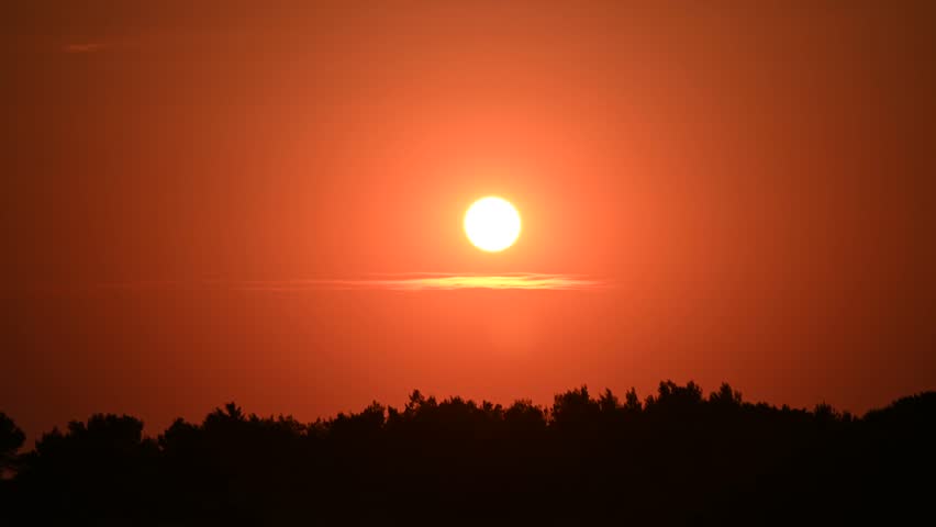 Vibrant sunset scene. Bright orange and red sunset above the forest. Dramatic evening sky.