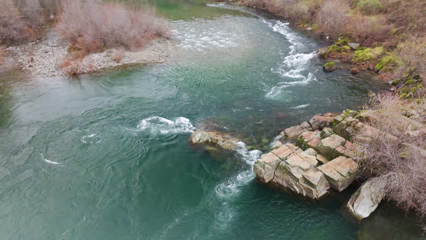 Rapids flowing over rocks in a swollen river.