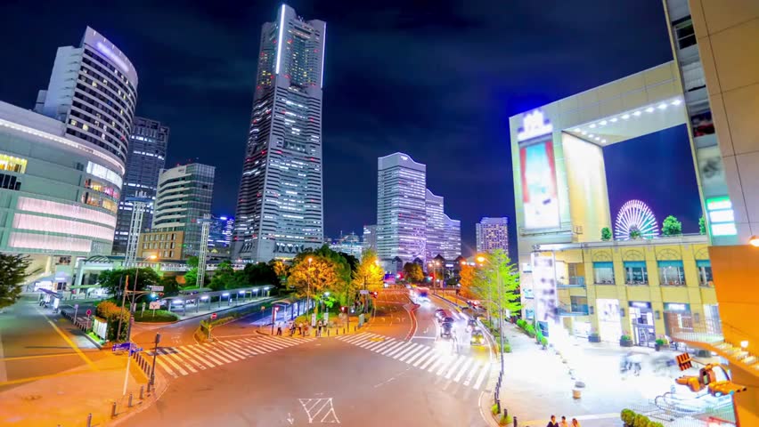 Night view of Yokohama city skyline with illuminated buildings and streets, vibrant lights reflecting urban energy along the waterfront in Japan.