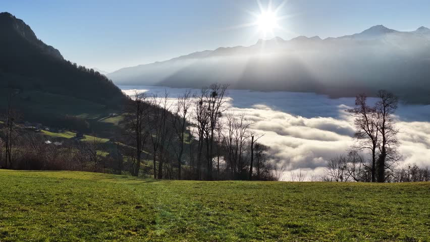 Sunlight over clouds filling a mountain valley.