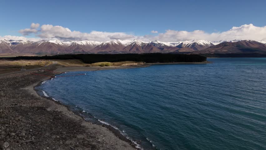 Stunning drone footage of the turquoise waters of Lake Pukaki with the snow-capped Southern Alps and Mount Cook in the background, captured in high-resolution 4K 60fps