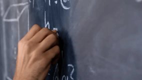 Writing on School Board. Close-up slow motion of female hand teacher writing symbols on chalkboard teaching physics in high school. Education and science concept. - Powered by Shutterstock - Get 15% off with code: PIKWIZARD15