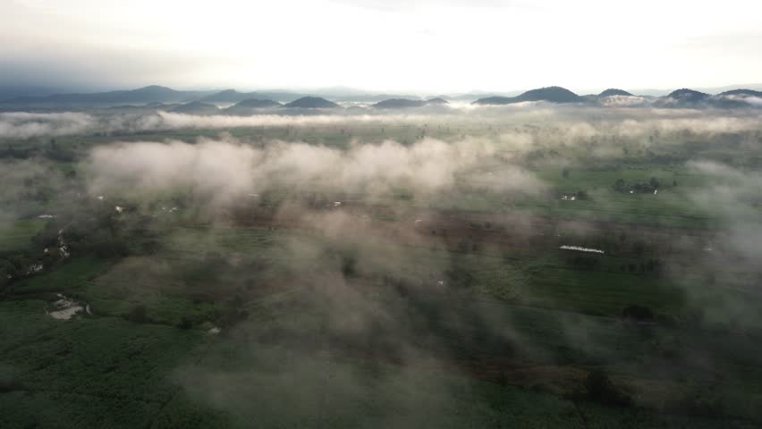 aerial fog valley farmland mountain sunrise mist landscape, soft morning light over green fields and rural plains, calm panorama with low cloud drifting above distant ridge