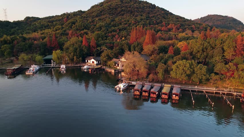 A cinematic aerial time-lapse of Hangzhou’s nightscape, where illuminated bridges and glowing skyscrapers reflect on tranquil lakes and canals, merging urban energy with serene waters under a moonlit, cloud-streaked sky.