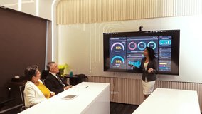 An Indian female presenter shares sales statistics and strategic insights on a large screen with Asian senior clients during a corporate seminar, fostering collaboration and professional planning. - Powered by Shutterstock - Get 15% off with code: PIKWIZARD15