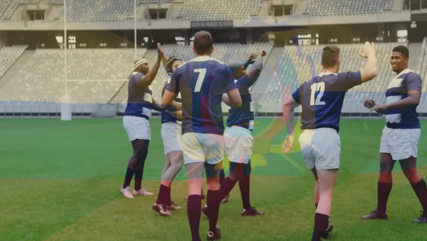 After scoring try rugby teammates forming circle on pitch raising arms and exchanging high-fives. Athletes, teamwork, celebration, camaraderie, sportsmanship, unity, competition