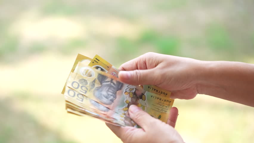 Hands counting and exchanging Australian dollar banknotes, symbolizing cash payment, financial transaction, personal finance, economy, savings, and everyday money exchange.