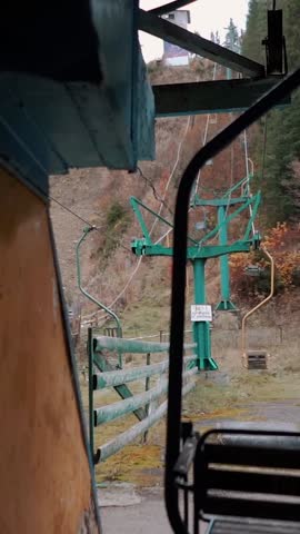 An old, abandoned stadium with a ski and snowboard slope overgrown with grass and weeds. A rusty metal ski lift. Memories and nostalgia for winter sports athletes