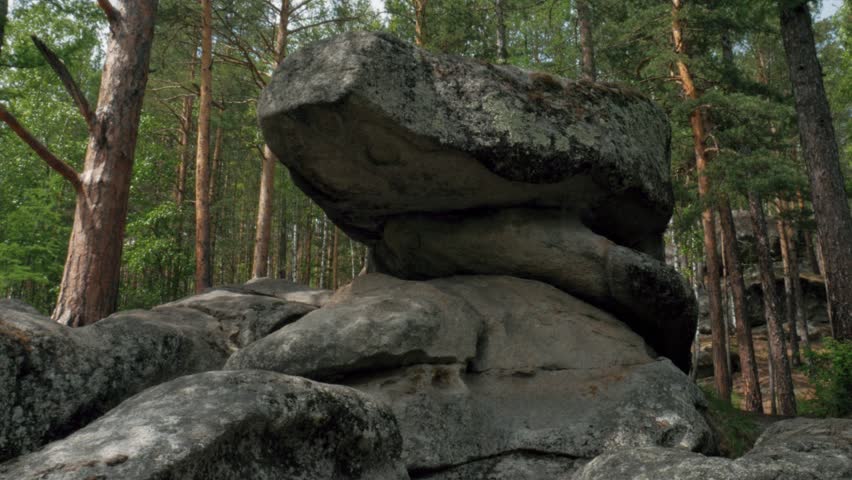 Large Unusually Shaped Rock Formation in Siberian Forest Static Shot. Static shot of a massive unique rock formation resembling a megalith or balanced stone illuminated by sun in the Siberian taiga.
