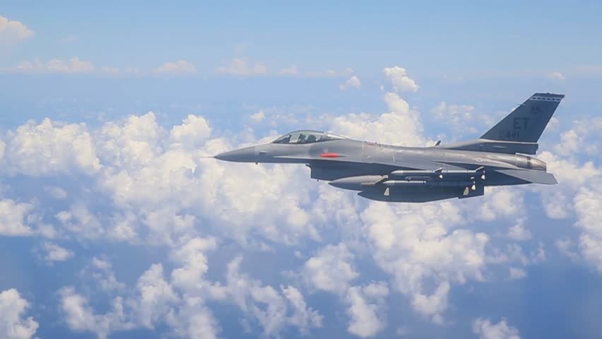 Modern Fighter Jet Flying Above Clouds in Clear Blue Sky