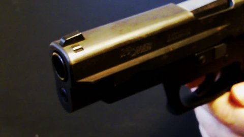 Close up of fingers on a trigger of a .45 caliber handgun pistol. This clip features the gun being pushed forward slowly as in the natural motion that occurs before the trigger is squeezed.