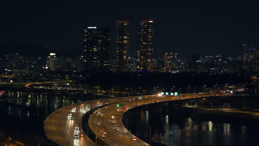 Night drone shot of car lights on highway ramps near Acro Forest and Galleria Foret skyscrapers in Seongsu-dong district of Seoul at night