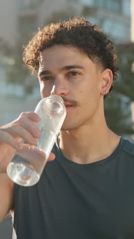 Sports, drinking water and man in city for exercise, workout and recovery for training outdoor. Morning, fitness and below of person with bottle for hydration, break and rest for wellness and health