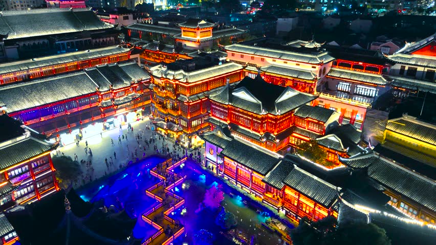 Aerial night shot of brightly illuminated traditional buildings and courtyards filled with people at Yuyuan Bazaar, Shanghai, China.