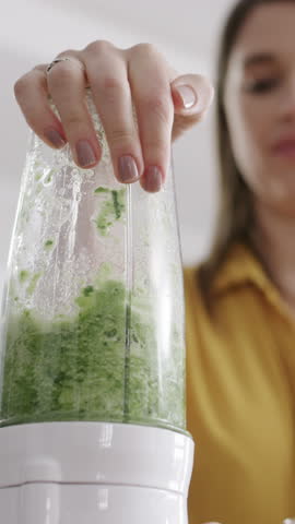 Woman, hand and blender with green juice or smoothie in kitchen for nutrition, vitamins or diet. Female person, nutritionist or mixer with ingredients or organic food for health detox in house