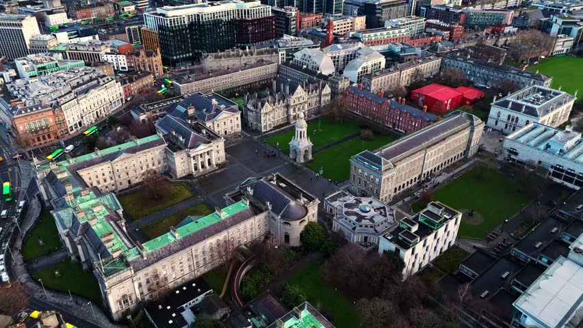 aerial drone shot capturing the trinity college university campus in the heart od the Irish capital of Dublin at sunrise with students and tourists alike wandering about with fields and trees around