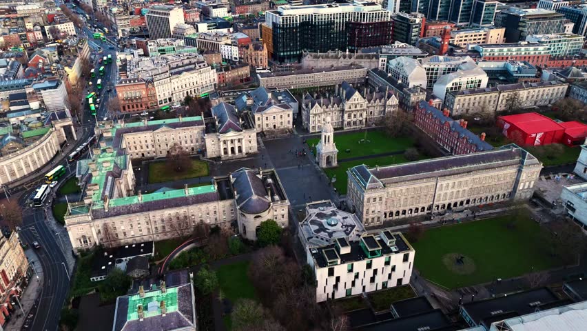 aerial drone shot capturing the trinity college university campus in the heart od the Irish capital of Dublin at sunrise with students and tourists alike wandering about with fields and trees around