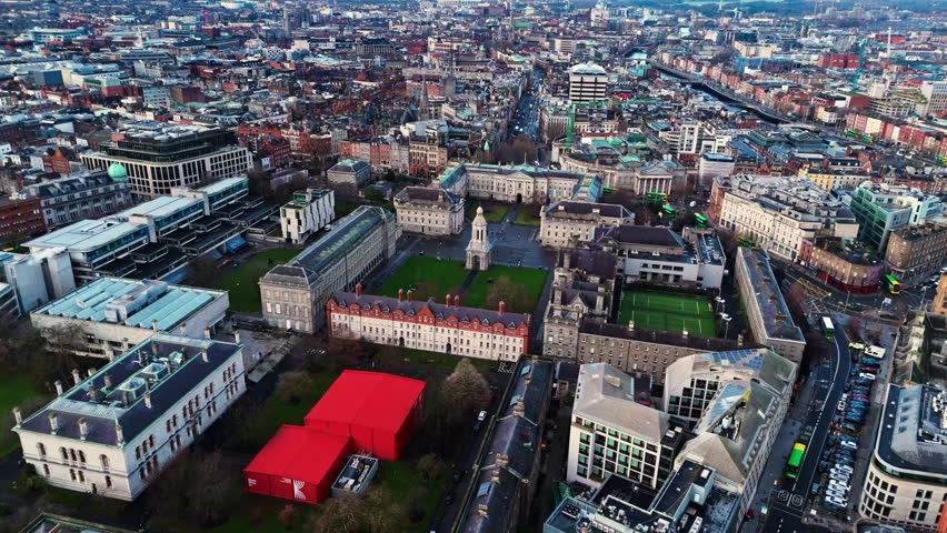 aerial drone shot capturing the trinity college university campus in the heart od the Irish capital of Dublin at sunrise with students and tourists alike wandering about with fields and trees around