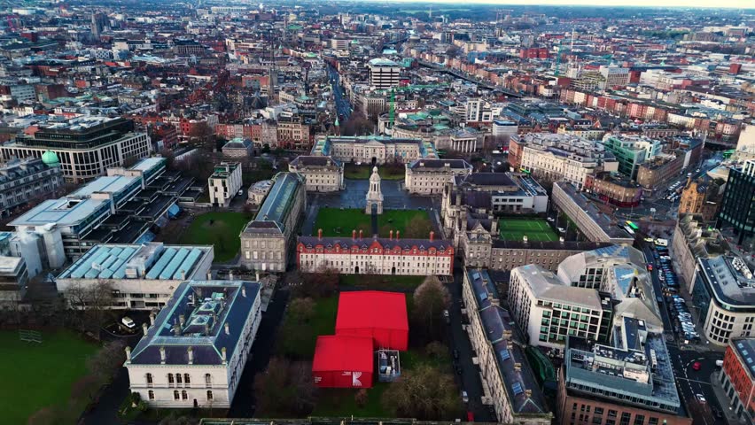 aerial drone shot capturing the trinity college university campus in the heart od the Irish capital of Dublin at sunrise with students and tourists alike wandering about with fields and trees around