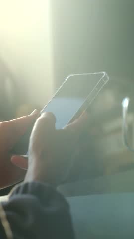 Close up hands person holding smartphone, scrolling through social media feed with thumb in brightly lit environment, showing modern communication, connection. Hands scrolling on smartphone screen